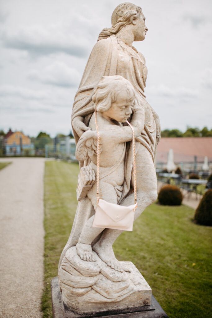 Historische Skulptur mit Handtasche in Dresden Schloss Wackerbarth mit eleganter Brauttasche – stilvolle Hochzeitsinspiration.